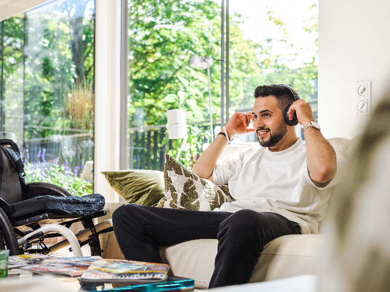 Mann auf einem Sofa in einem privaten Wohnzimmer mit Kopfhörern auf dem Kopf, entspannt 