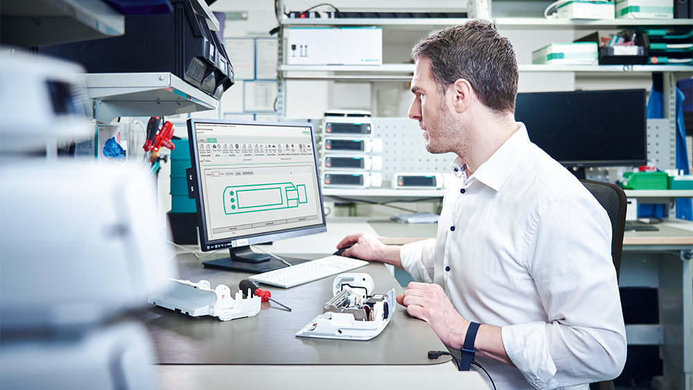 Biomed sitzt vor seinem Computer und repariert eine Infusionspumpe