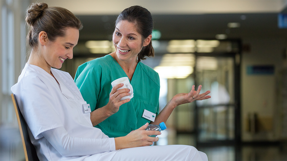 Zwei weibliche Pflegekräfte haben Spaß im Flur des Krankenhauses