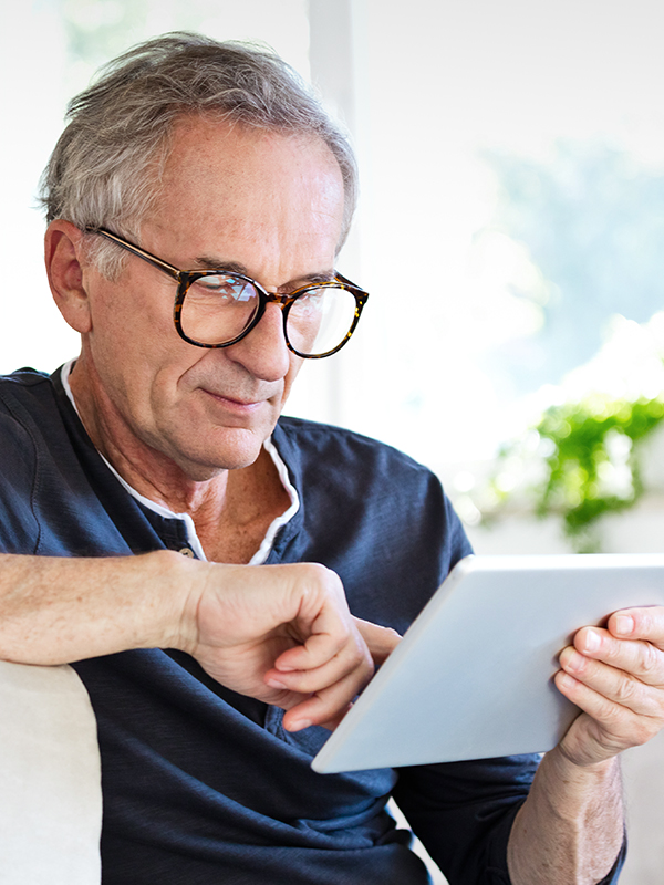Mann mit Brille schaut auf ein Tablet in den Händen