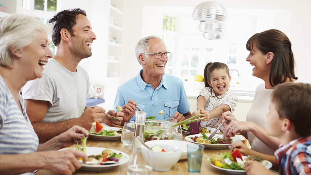 Eine Familie sitzt am Tisch und isst und lacht