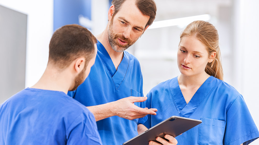 Drei Ärzte besprechen etwas auf einem Tablet