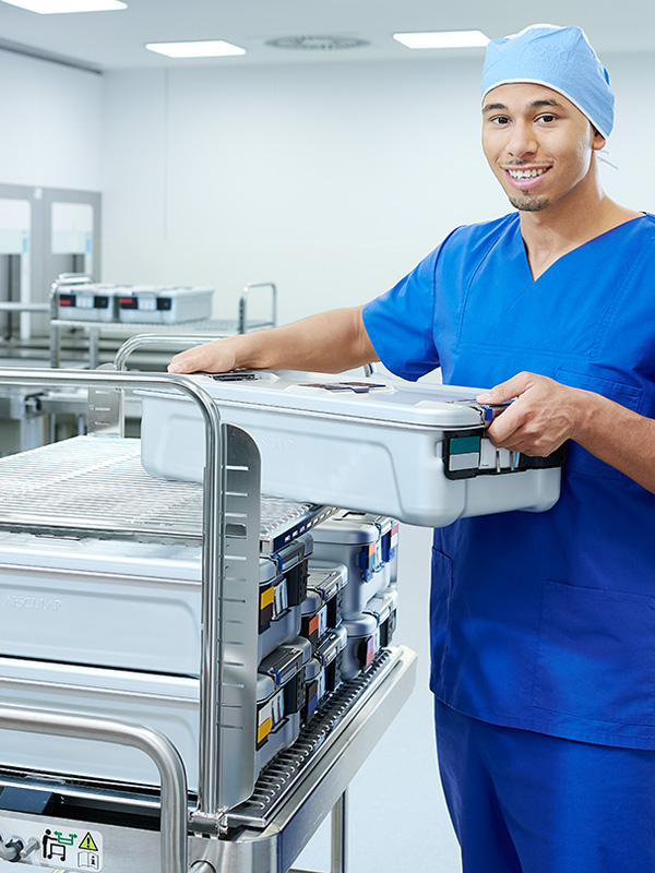 Ein männliches medizinisches Fachpersonal hält lächelnd einen riesigen Behälter