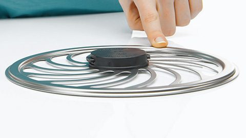 Eine Hand berührt einen radförmigen Metallgegenstand, der Teil eines medizinischen Geräts oder einer medizinischen Ausrüstung sein könnte